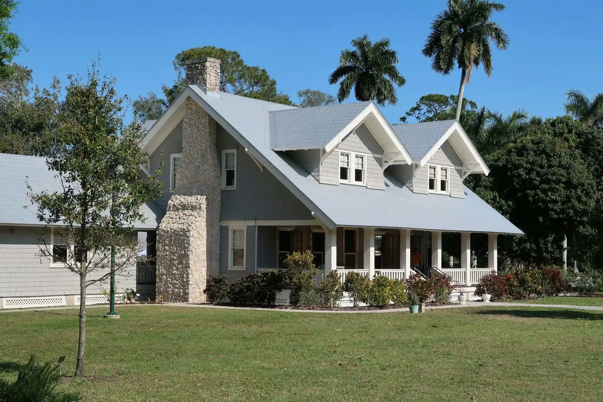 Gray Florida home with a porch and palm trees