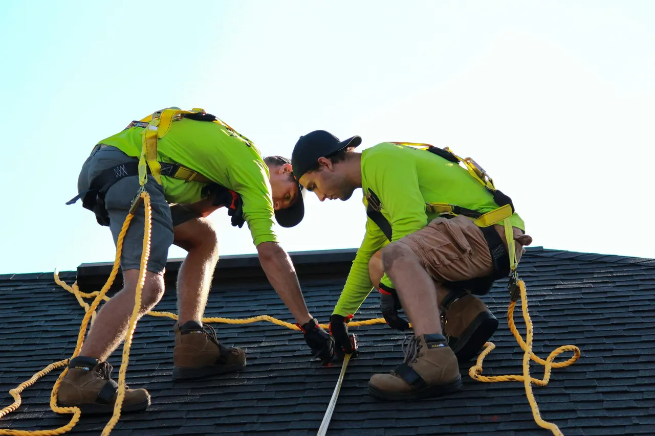 Roofers in hi-vis shirts working on a shingle roof